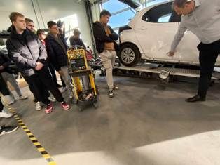 uczniowie ZSS na hali, prowadzący objaśnia na samochodzie sposób przygotowania samochodu do malowania