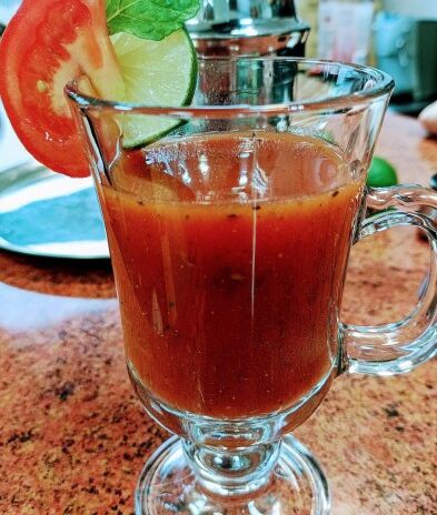 napój w wysokiej szklance ozdobiony pasterkami cytryny pomidora i listkiem mięty